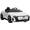 A white Audi electric car for children with black details, featuring a steering wheel, LED headlights, and a horn.